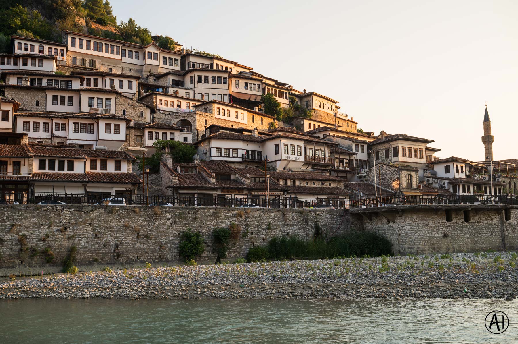 Hillside houses above a stone river wall
