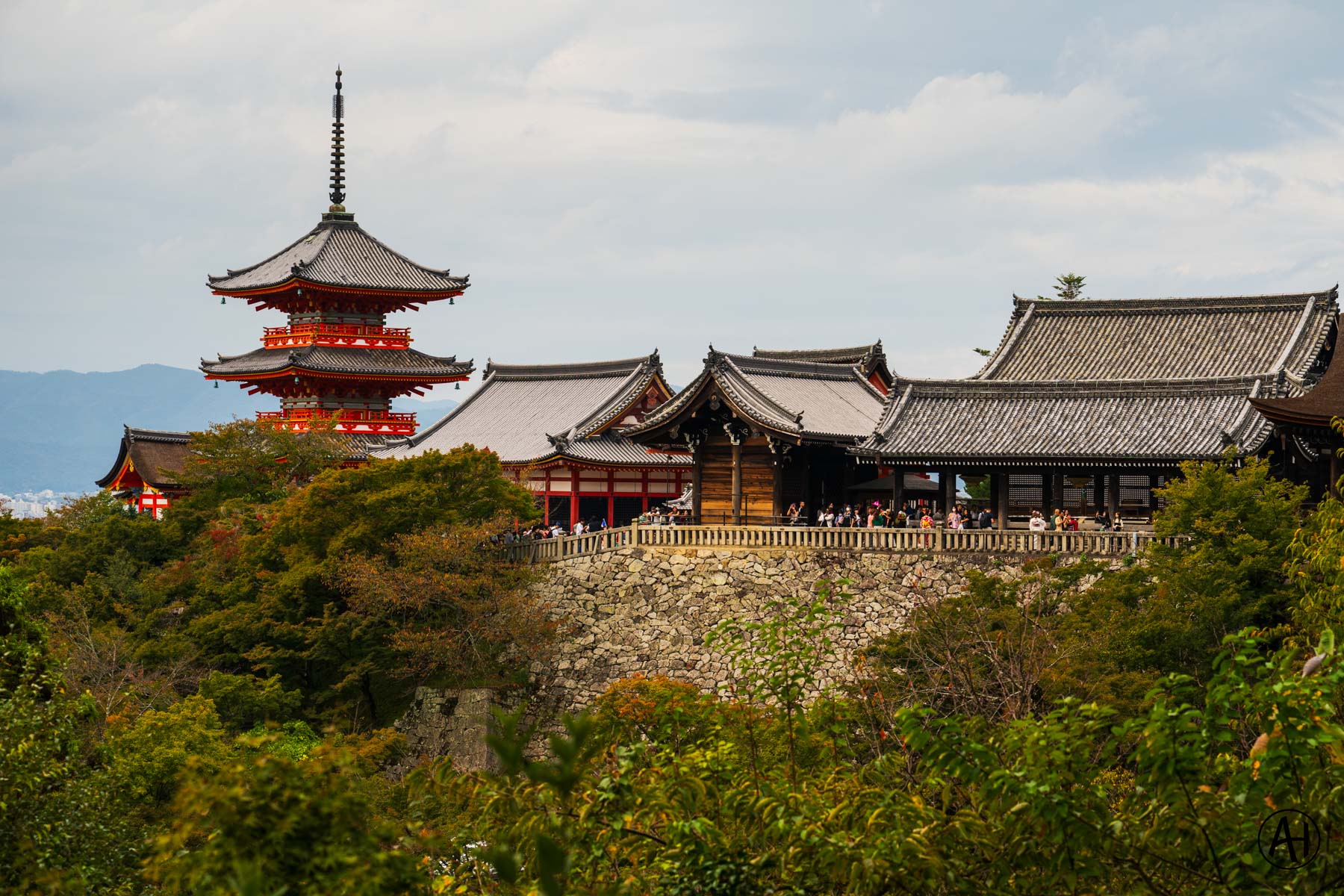 A pagoda and temple roofs above a wooded hillside