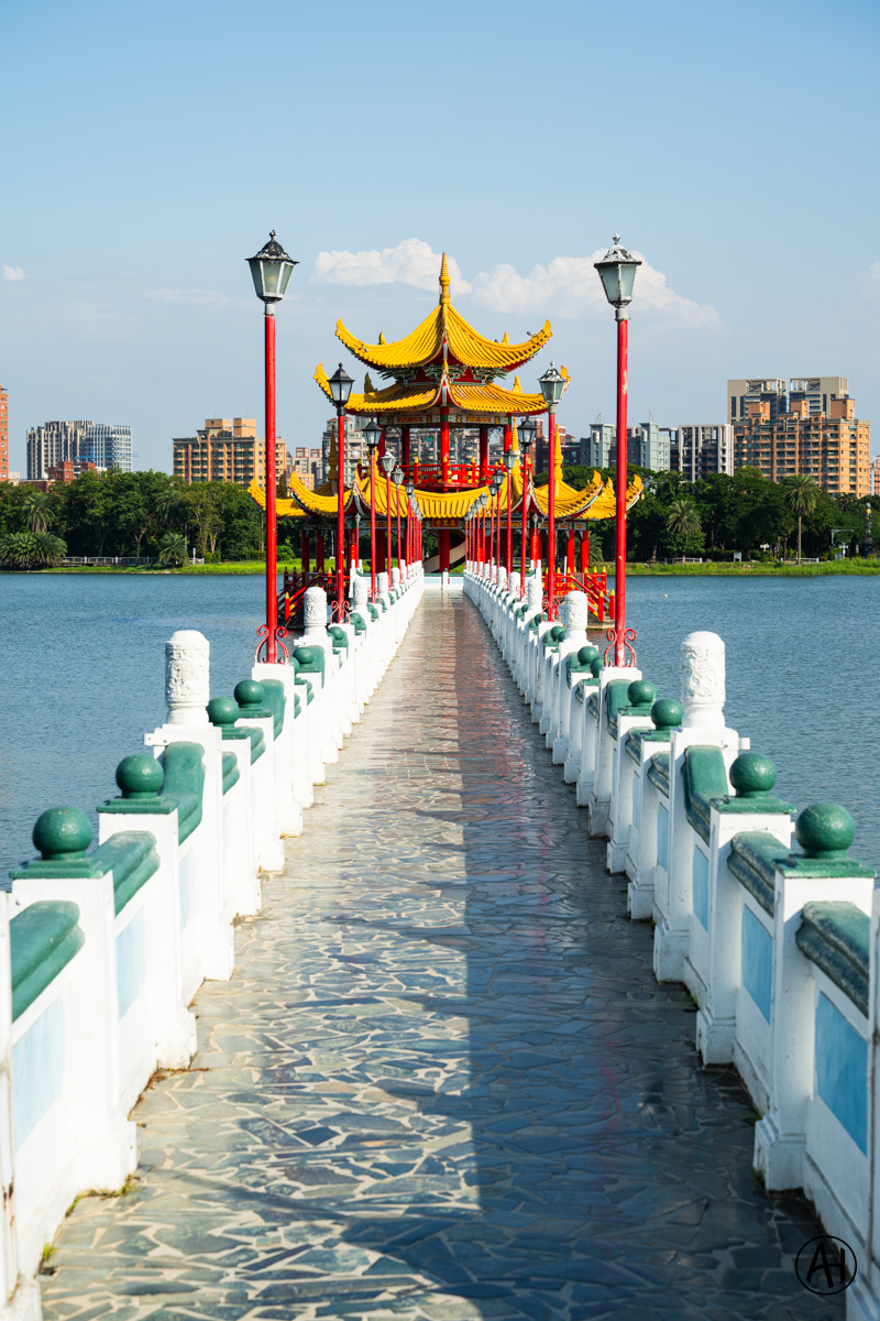 A red and gold pavilion at the end of a bridge over Lotus Pond